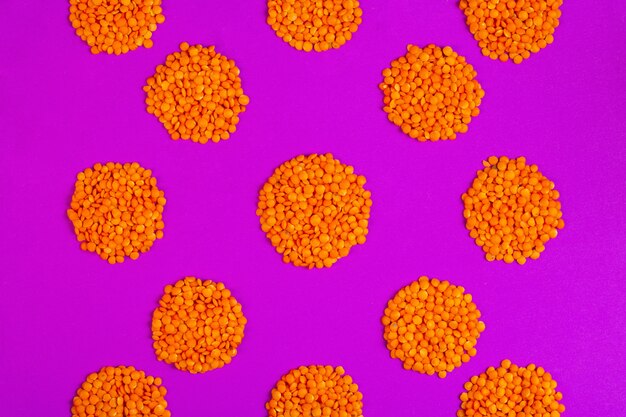 Top view of red raw lentils in a shape of cirle on purple