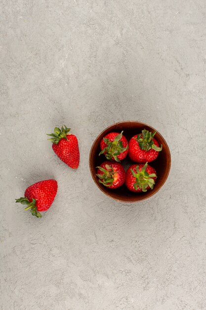 top view red strawberries fresh ripe mellow inside and outside brown pot on the light floor