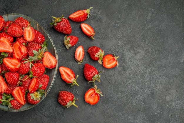 Top view red strawberries sliced and whole fruits on grey background