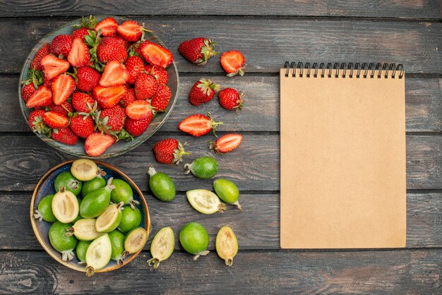 Top view red strawberries with fresh feijoas on dark wooden rustic desk