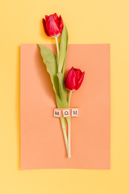 Free Photo top view of red tulip flowers with mother's day greeting card over yellow background