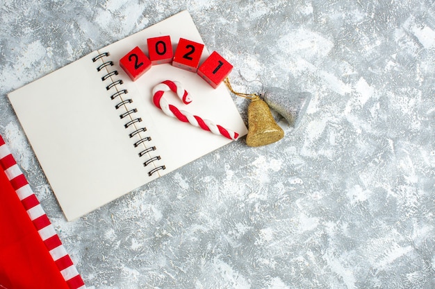 Free Photo top view red wood blocks xmas candy on notebook xmas bells on grey white table with free place