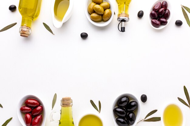 Top view red yellow black olives in spoons with oil bottles and copy space