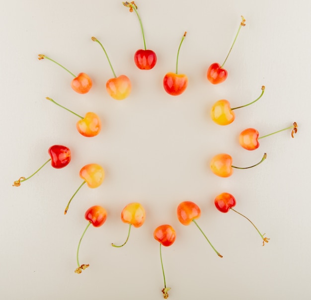 Free photo top view of red and yellow cherries set in round shape on white surface