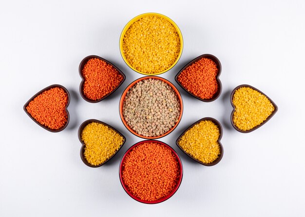 Top view red, yellow and green lentils in different colored and heart shaped blows