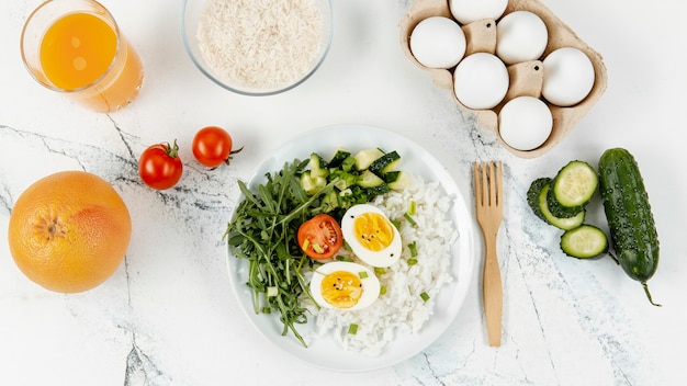 Top view of rice and eggs on plate with orange juice