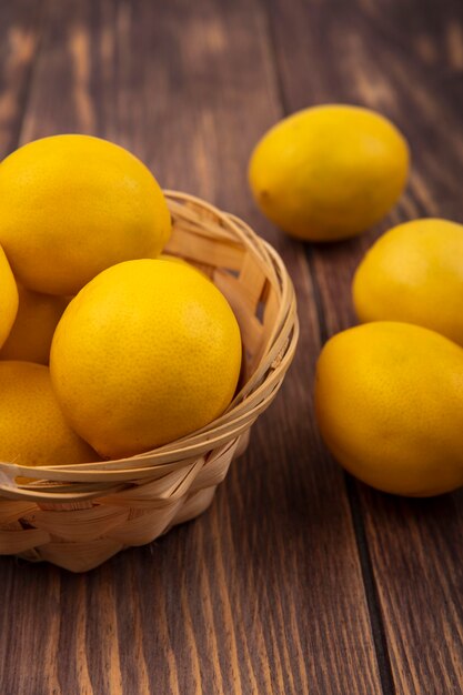 Top view of rich in vitamin c lemons on a bucket with lemons isolated on a wooden wall