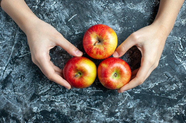 Top view ripe apples female hands on grey background with copy place