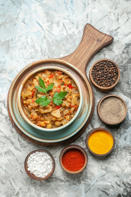 Free photo top view of roasted eggplant salad in bowl and different spices in bowls on grey surface