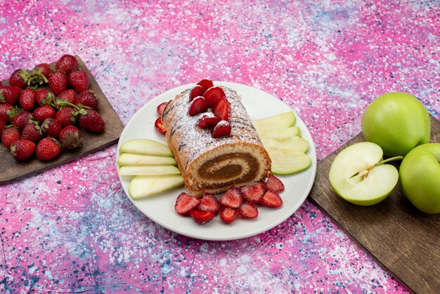 Top view roll cake slices with apples and strawberries inside white plate on the colored desk cake biscuit sweet fruit