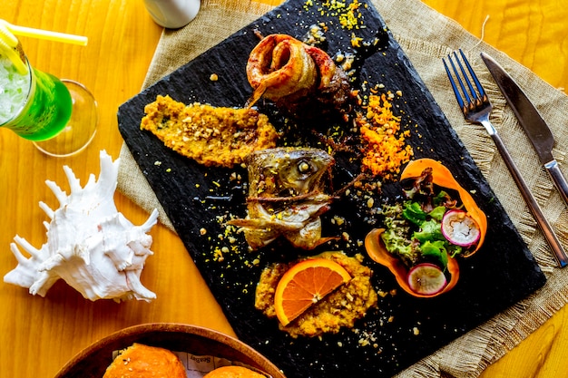 Free photo top view rolled fried fish with vegetable salad and orange slice decor