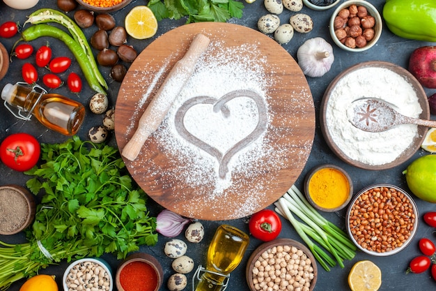 Top view rolling pin heart imprint in powdered flour on round dough board