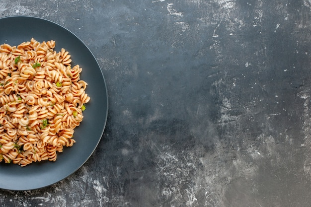 Top view rotini pasta on round plate on dark surface free space