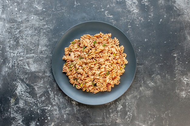 Top view rotini pasta on round plate on dark surface with copy place