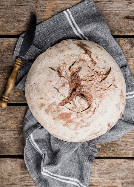 Free photo top view round bread with knife on cloth