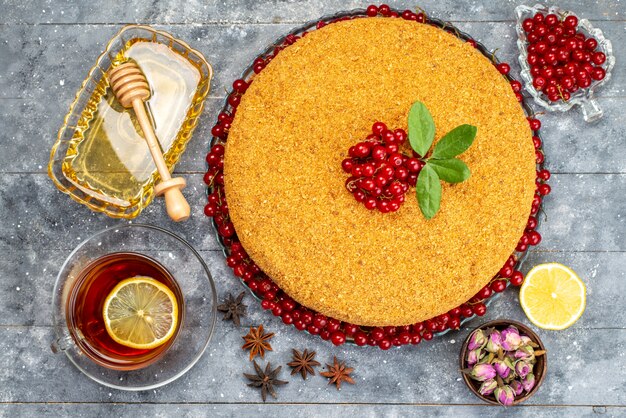 A top view round honey cake delicious and baked with red cranberries on the grey desk cake biscuit sugar  bake