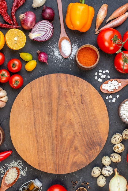 Top view round wood board rice sea salt in wooden spoons tomatoes quail eggs on black table