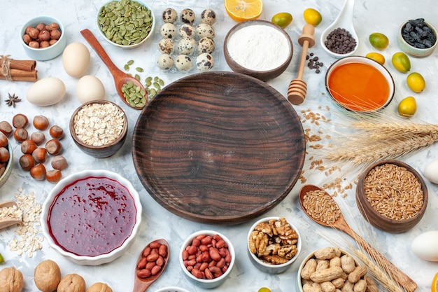 Top view round wooden plate with jelly eggs different nuts and seeds on white dough sugar sweet color biscuit nut photo cake