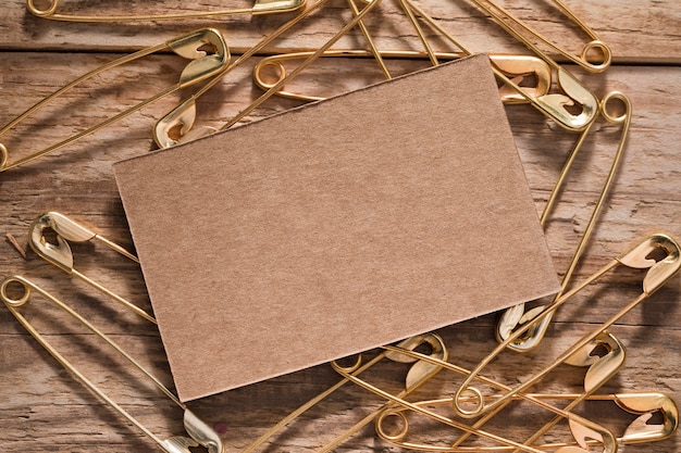 Free photo top view of safety pins on wooden surface with card