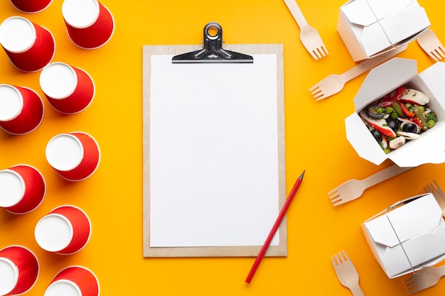 Free photo top view salad with clipboard on yellow background