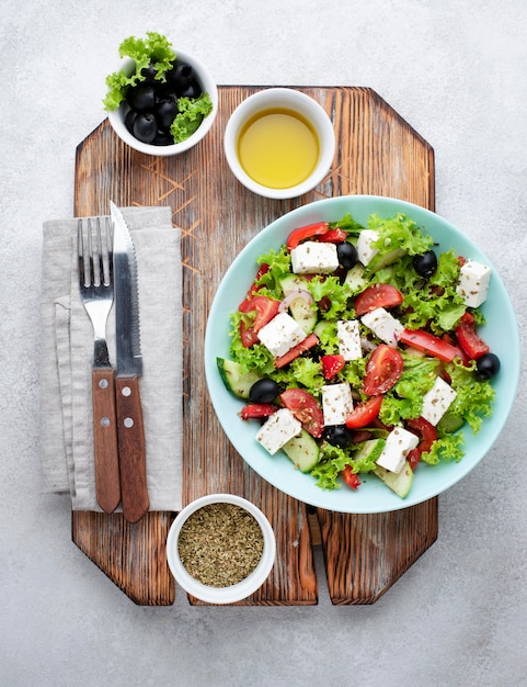 Top view salad with feta cheese on cutting board with olives and herbs