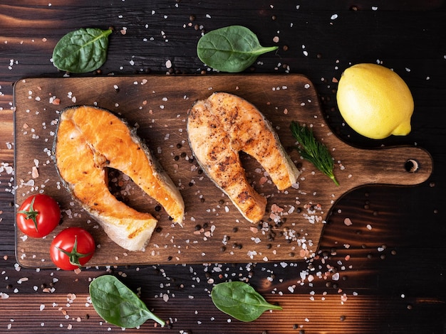 Free photo top view of salmon rings cooked seasoned with salt and pepper. lemon and tomatoes placed near salmon