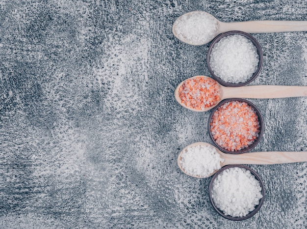 Free photo top view of salt in bowls and wooden spoons with himalayan salt