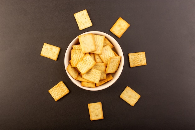 Free photo a top view salted crisps tasty crackers cheese inside white plate on the dark background snack salt crisp food