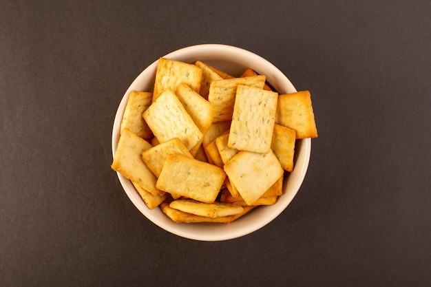 Free Photo a top view salted crisps tasty crackers cheese inside white plate on the dark background snack salt crisp food