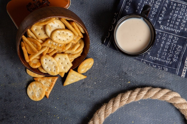 Free photo top view salted different crackers with cup of milk on the grey background cracker crisp snack photo