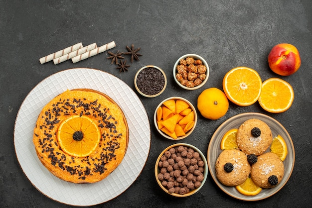 Top view sand cookies with orange slices and delicious pie on grey surface fruit biscuit cookie sweet tea