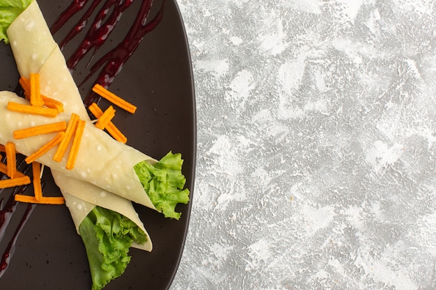 Free Photo top view of sandwich rolls with vegetables and green salad along with rusks inside dark plate