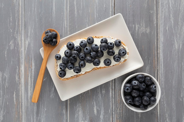 Free photo top view sandwich with cream cheese and blueberries on plate with spoon