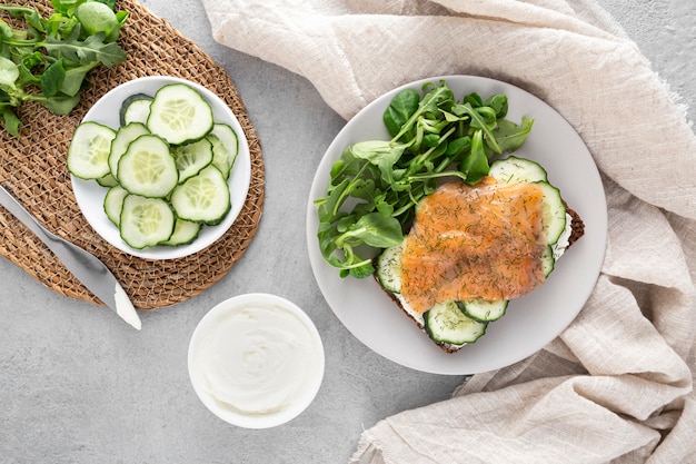 Free photo top view sandwich with cucumbers and salmon on plate with spinach