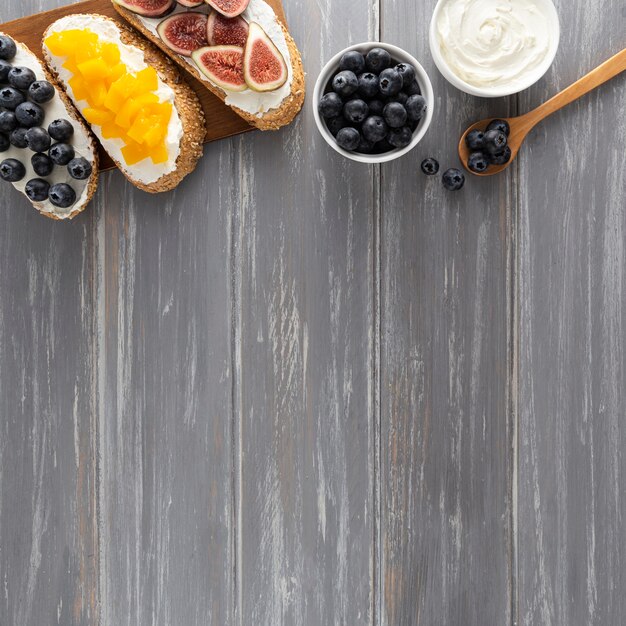 Top view sandwiches with cream cheese and fruits with copy-space