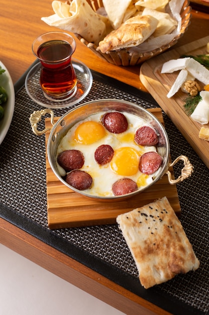 A top view sausage with eggs along with tea and bread loafs on the restaurant table food meal breakfast