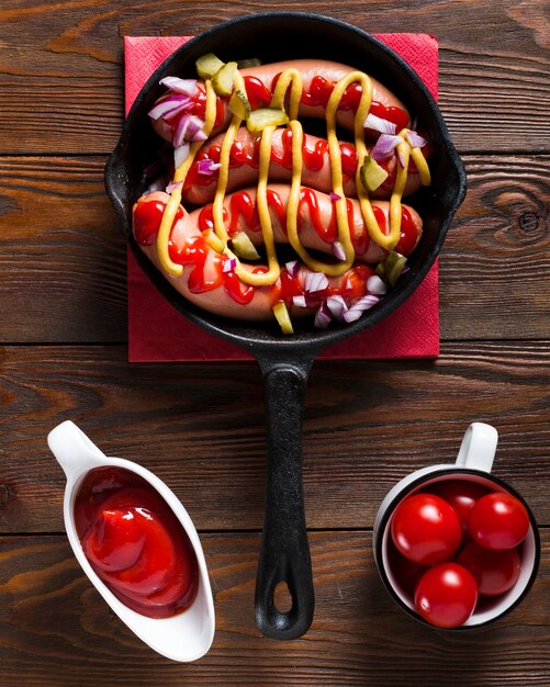 Top view sausages in pan with sauces and cherry tomatoes