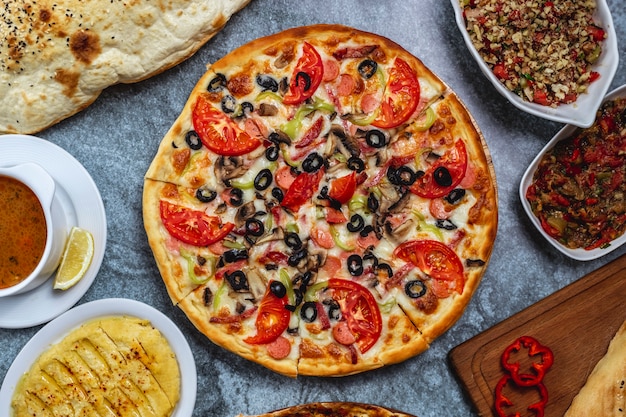 Top view sausages pizza with black olive bell pepper tomato and cheese on the table