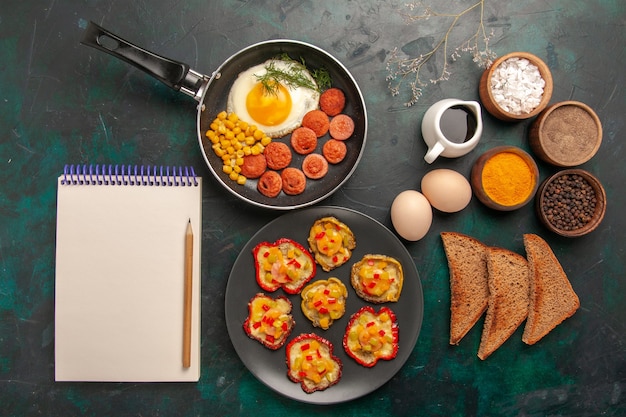 Free photo top view scrambled eggs with sausages bread and different seasonings on dark background