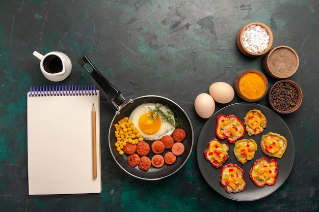 Free photo top view scrambled eggs with sausages and different seasonings on dark background