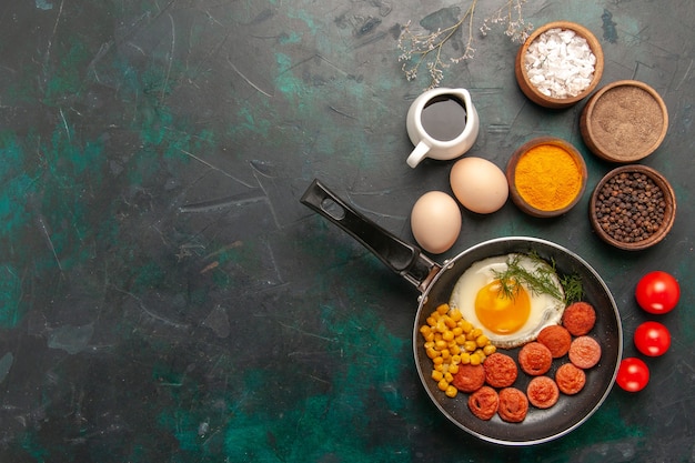 Free photo top view scrambled eggs with sausages and different seasonings on the dark green background