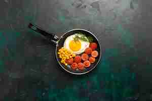 Free photo top view scrambled eggs with sausages and greens on dark-green background