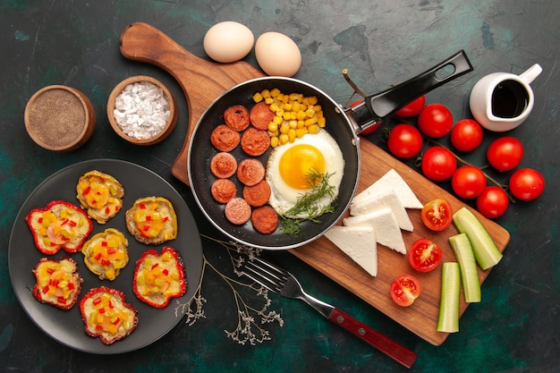 Free photo top view scrambled eggs with sliced sausages fresh tomatoes and raw eggs on dark background