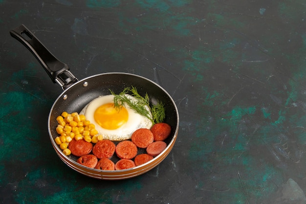 Free photo top view scrambled eggs with sliced sausages and greens inside pan on dark background