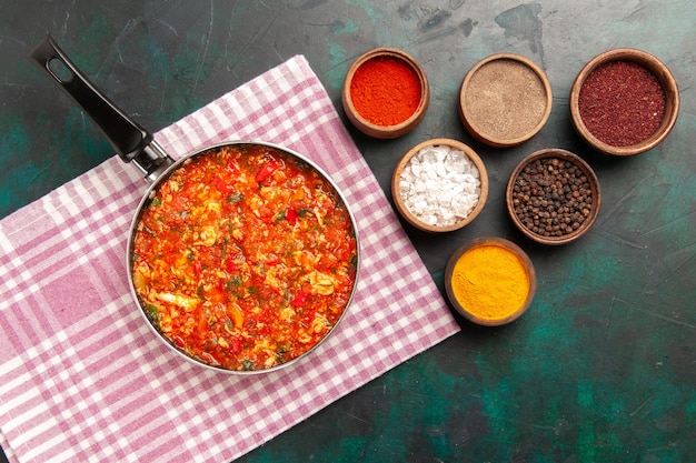 Free photo top view scrambled eggs with tomatoes and different seasonings on the dark green background