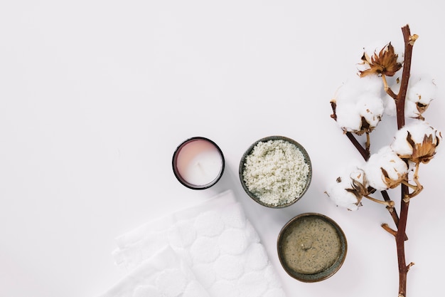 Free photo top view of scrubs; candle; napkin and cotton twig on white surface