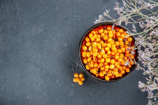 Top view sea buckthorn in bowl dried flower branch on dark red table free place