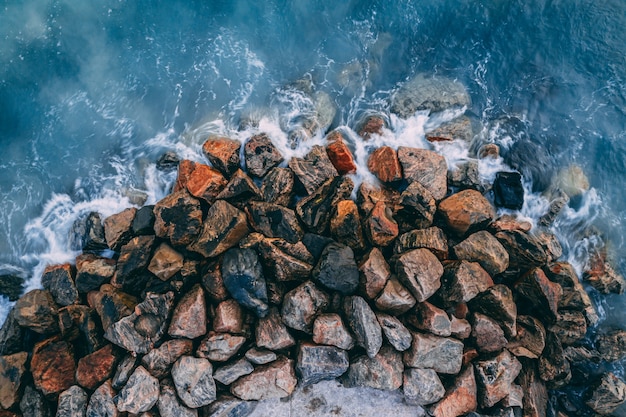 Top view of sea waves breaking on coastal stones