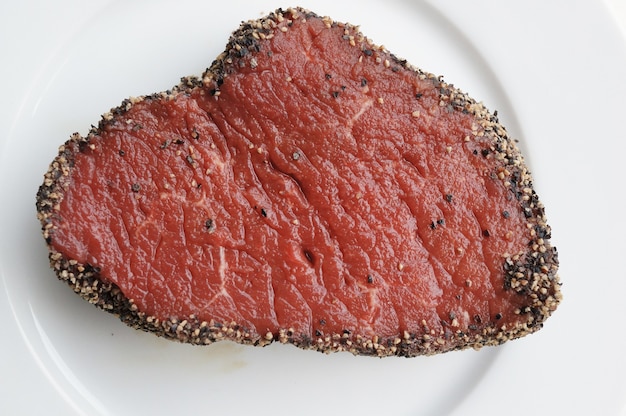 Top view of a seasoned raw steak on a plate on the table