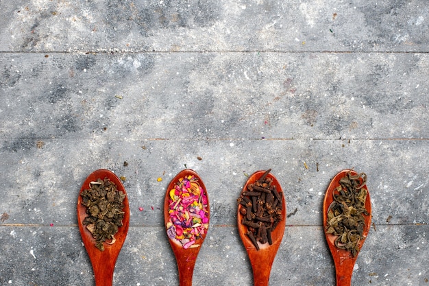 Free photo top view seasoning composition different colored inside spoons on a grey desk tea dry plant color